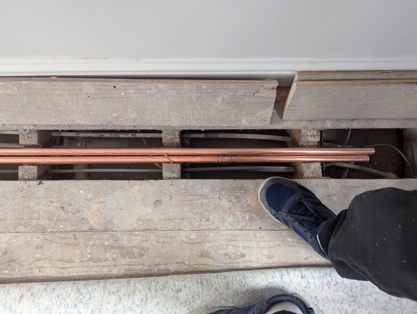 Copper central heating pipework running between floor joists under lifted floorboards