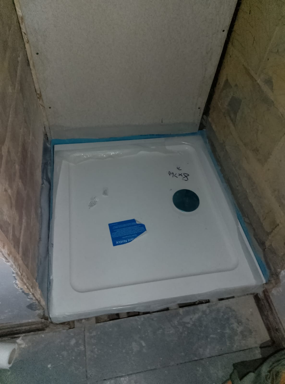 New white shower tray fitted and sealed into a tiled alcove