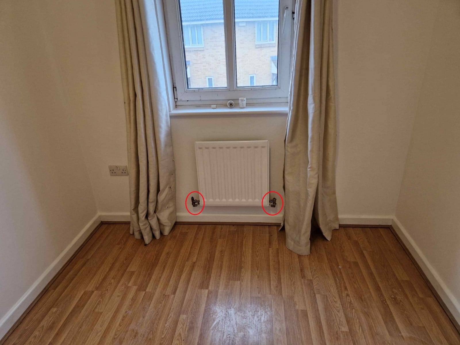 White panel radiator under a window with new valves fitted on each side